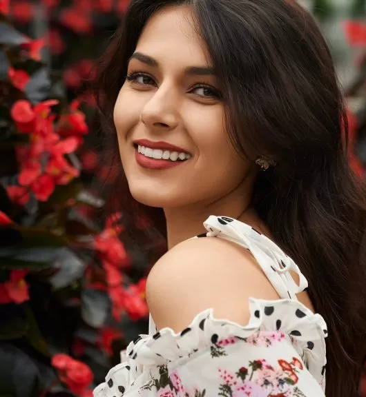 Portrait of smiling beautiful brunette woman in cute dress and in red lips on flowers background. Concept of professional photossesion in modern greenhouse.